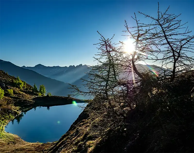 Mann steht oberhalb eines Bergsees am Gipfel eines Berges