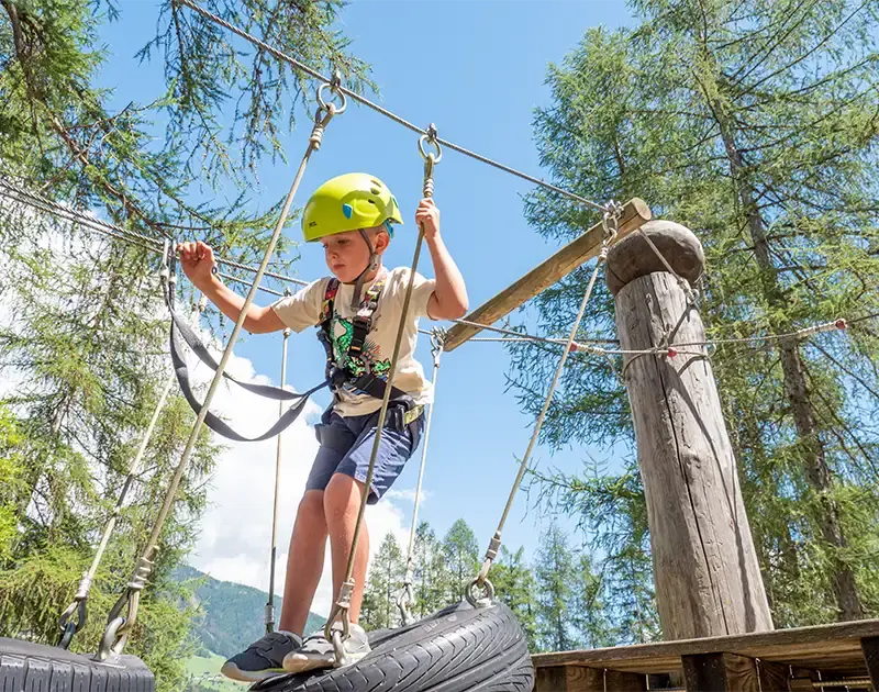Kind geht über einen Kletterweg im Kinderspielplatz Wichtelpark in Sillian