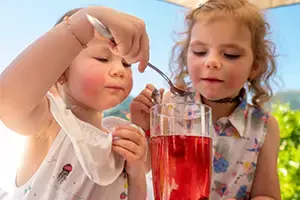 2 Girls drink a fruit juice in the garden