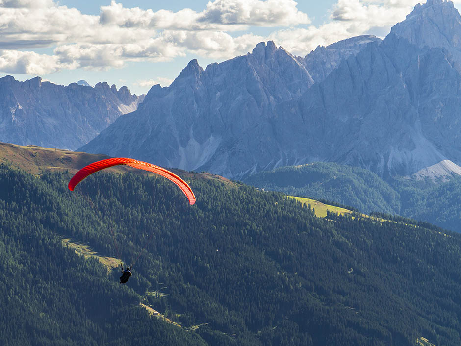 Paragleiter gleitet vom Thurntaler ins Tal, im Hintergrund die Dolomiten